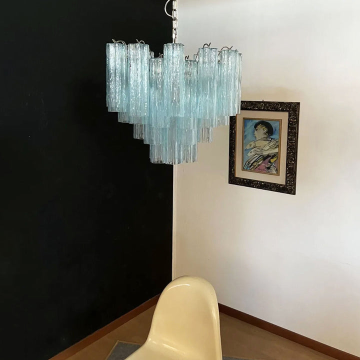 Murano Star Tube Chandelier with turquoise glass against a black accent wall with a white chair