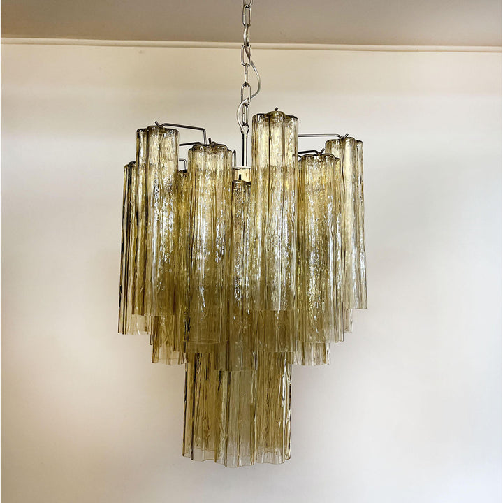 Murano Glass Tube Chandelier with amber gold glass lit with warm light on a white ceiling
