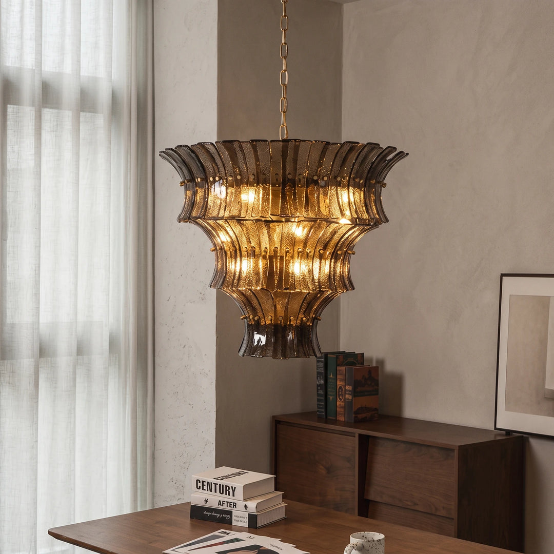 Amber fluted chandelier glowing above a vintage desk and stacked books