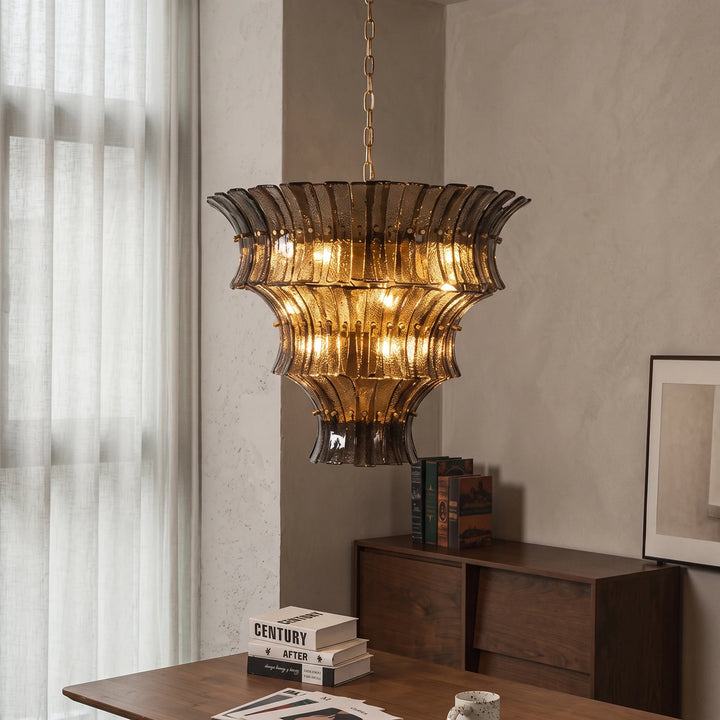 Amber fluted chandelier glowing above a vintage desk and stacked books