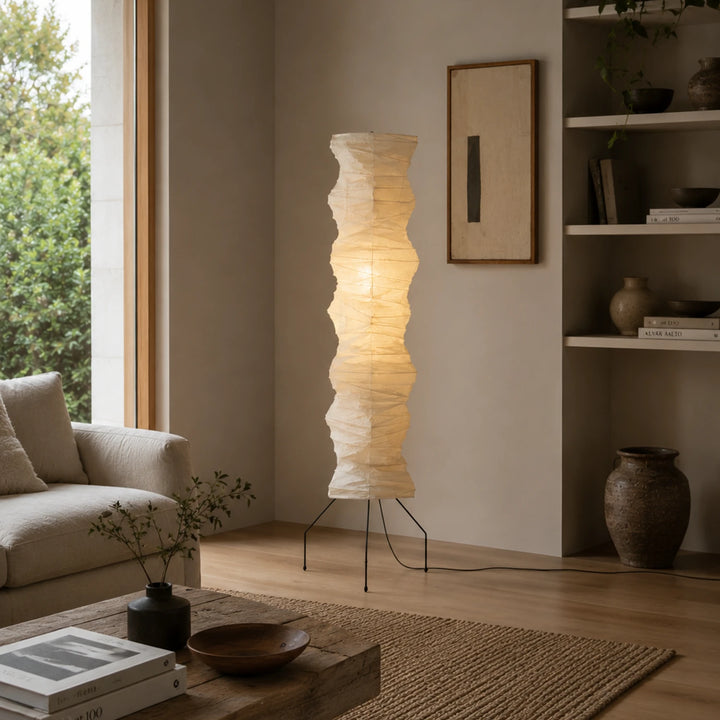 Paper floor lamp beside an armchair in a living room with garden views