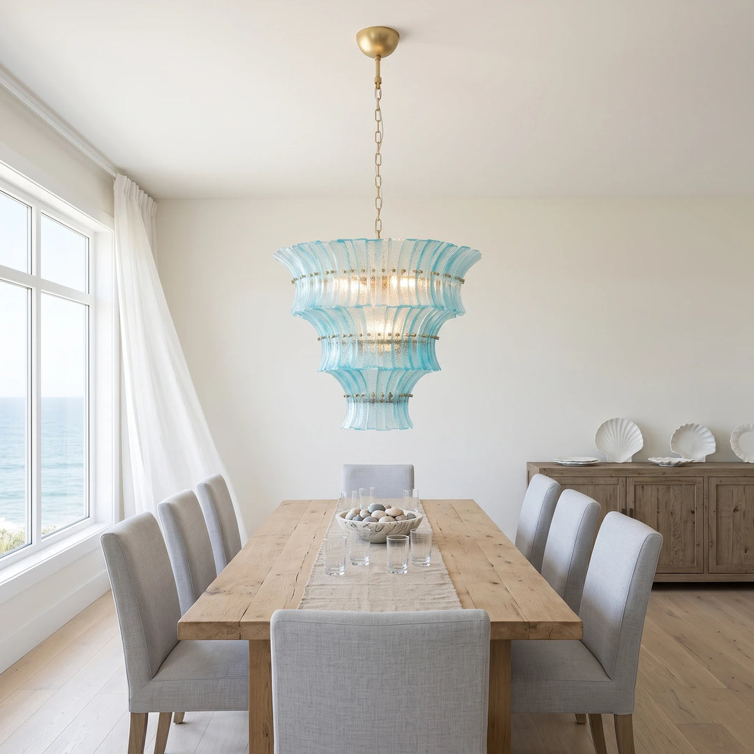 Aqua glass chandelier over a wooden dining table in a breezy coastal room