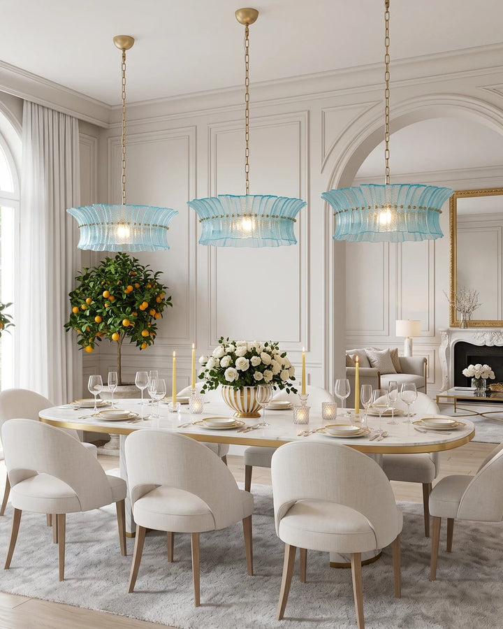Three aqua glass chandeliers spaced above a long oval dining table