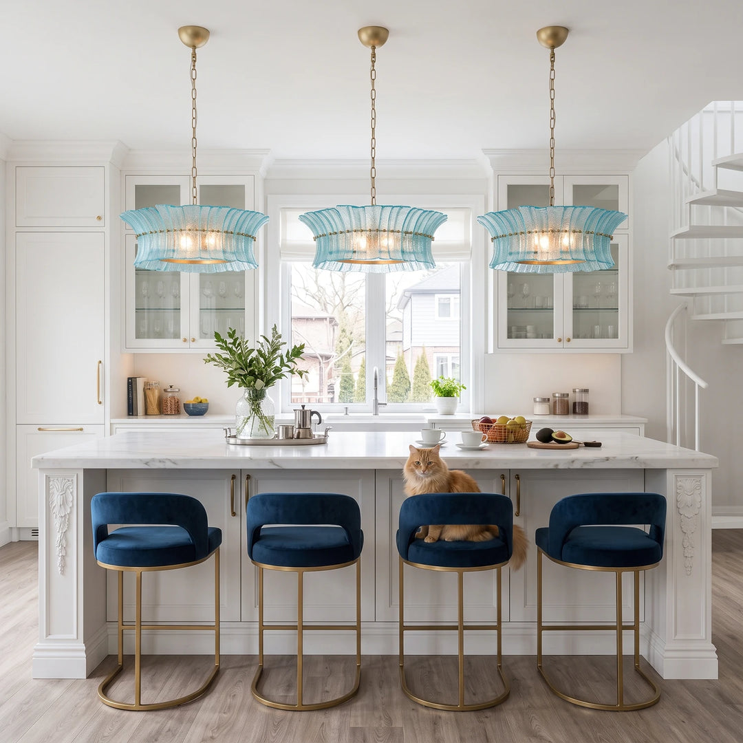 Three aqua glass pendants hanging above an island with navy velvet stools