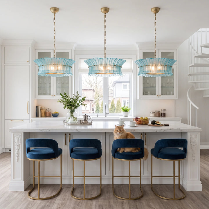 Three aqua glass pendants hanging above an island with navy velvet stools