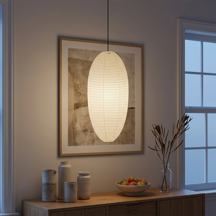 Oval paper pendant glowing above a bedside table in the evening