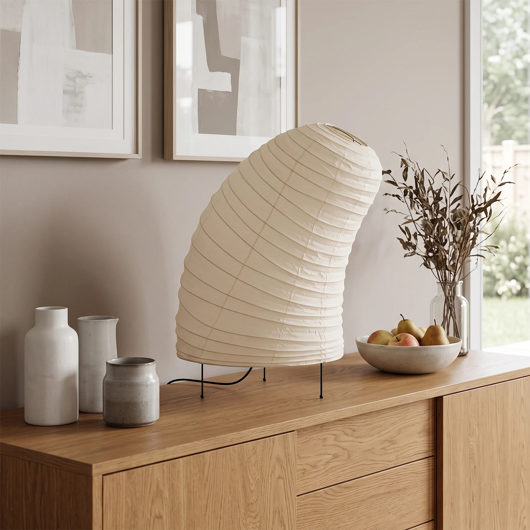 Curved paper table lamp on a wooden console beneath a round mirror