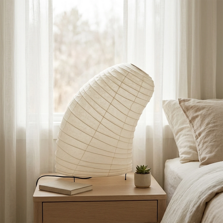 Curved paper table lamp on a side table beside a soft linen sofa