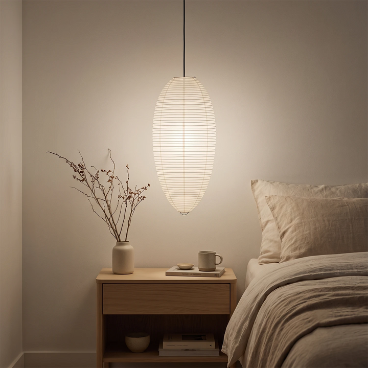Oval paper pendant above a dining table beside a dark picture window