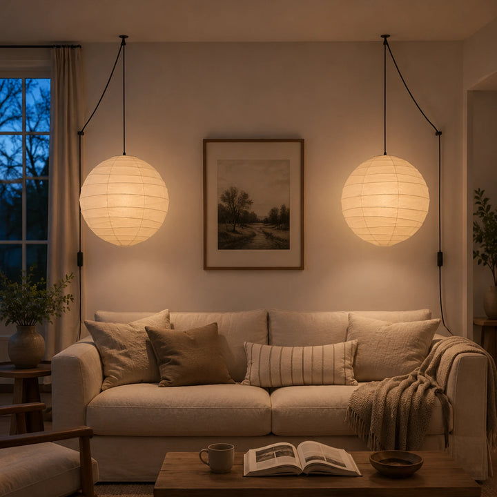 A pair of paper pendants glowing warm in a living room at night