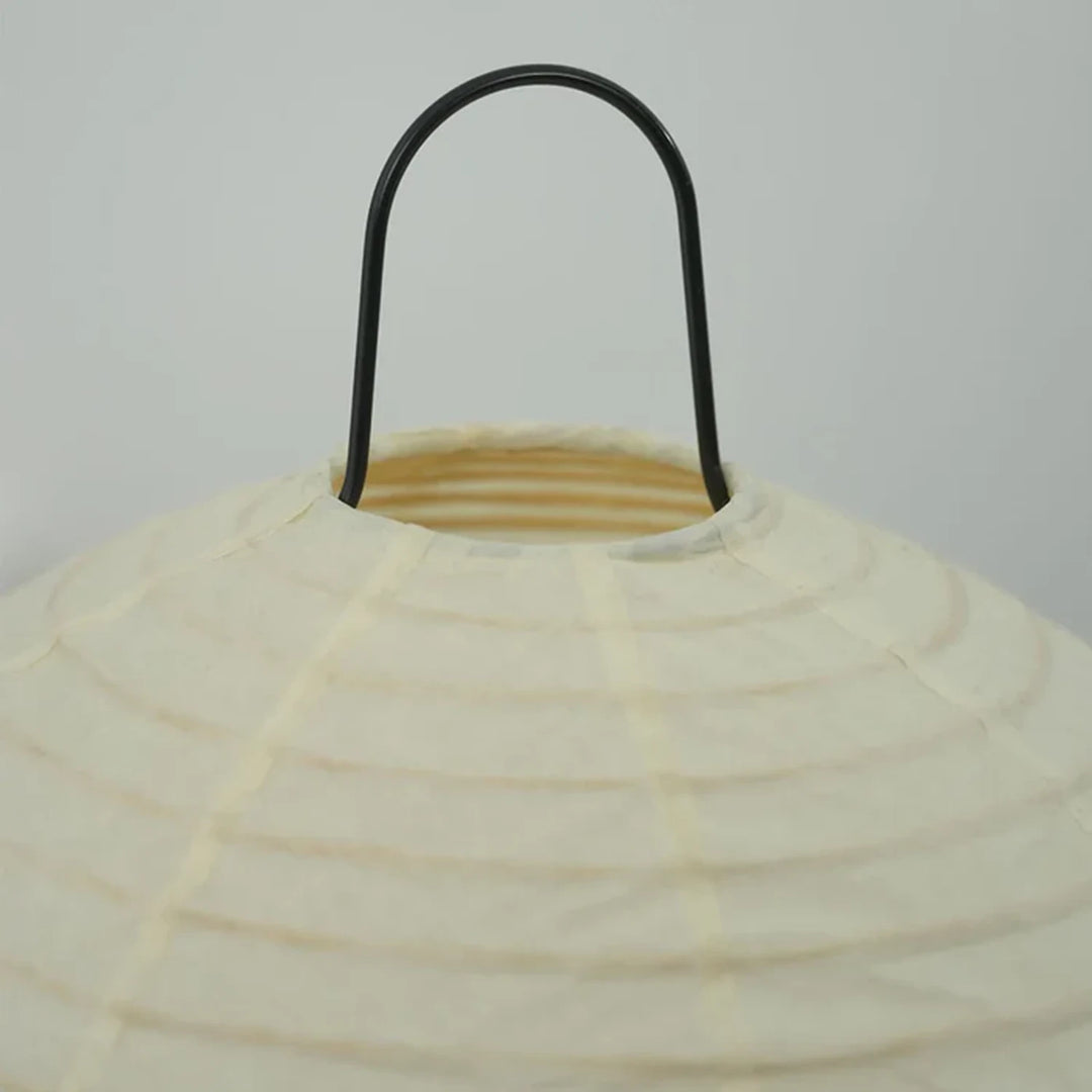 Detail of the curved black metal handle loop at the top of the paper lamp shade