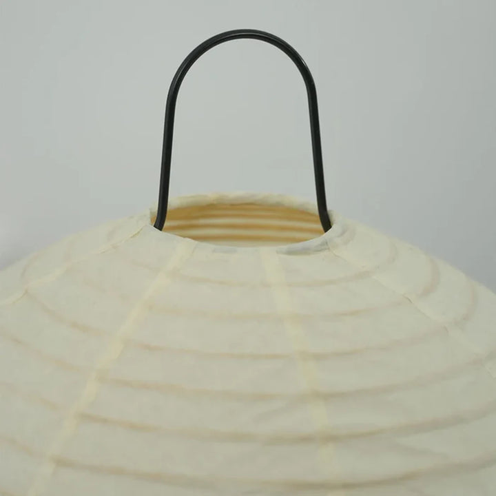 Detail of the curved black metal handle loop at the top of the paper lamp shade