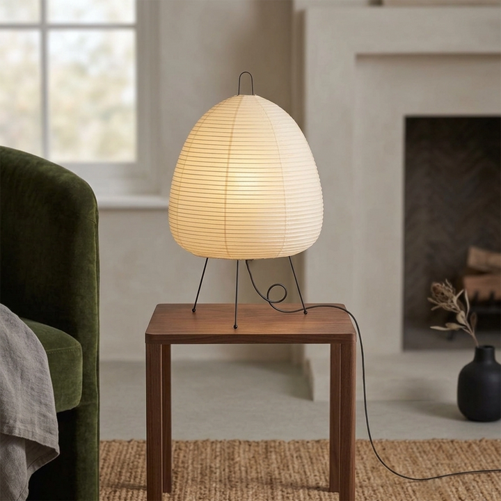 Japandi paper table lamp on a side table next to a green velvet armchair