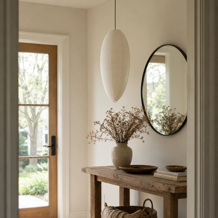 Oval paper pendant in an entryway beside a round mirror and console table