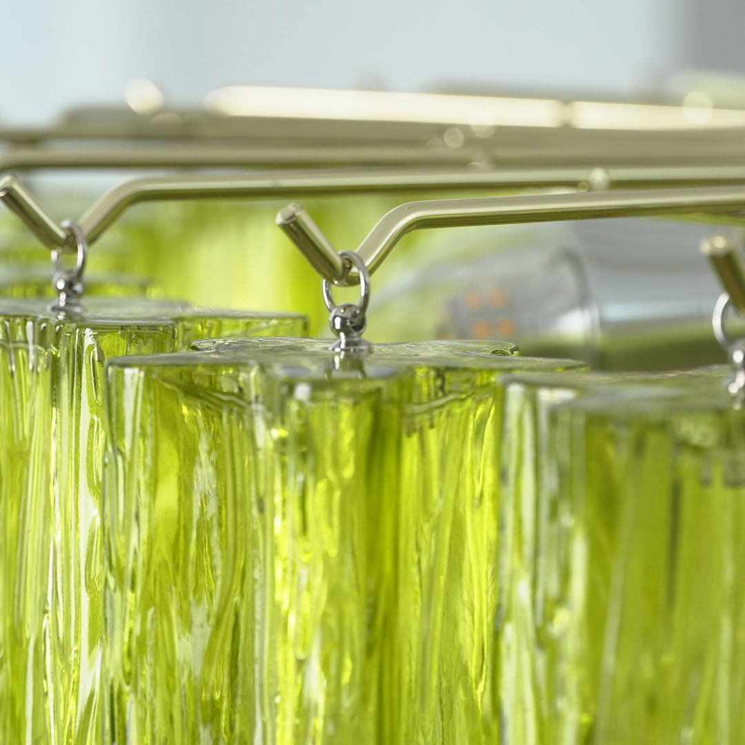 Close-up of gold metal clips holding the lime green Murano glass tubes in place
