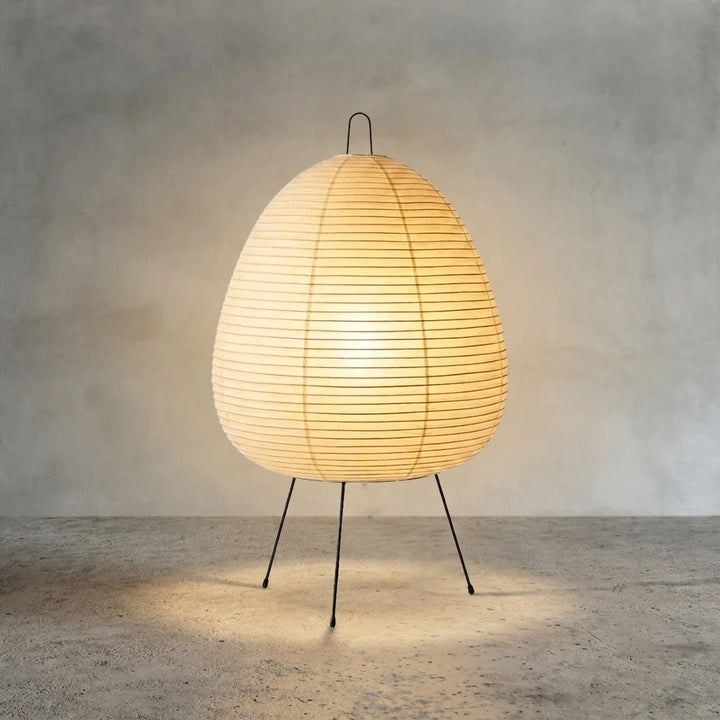 The same paper table lamp switched on, glowing with a warm amber light