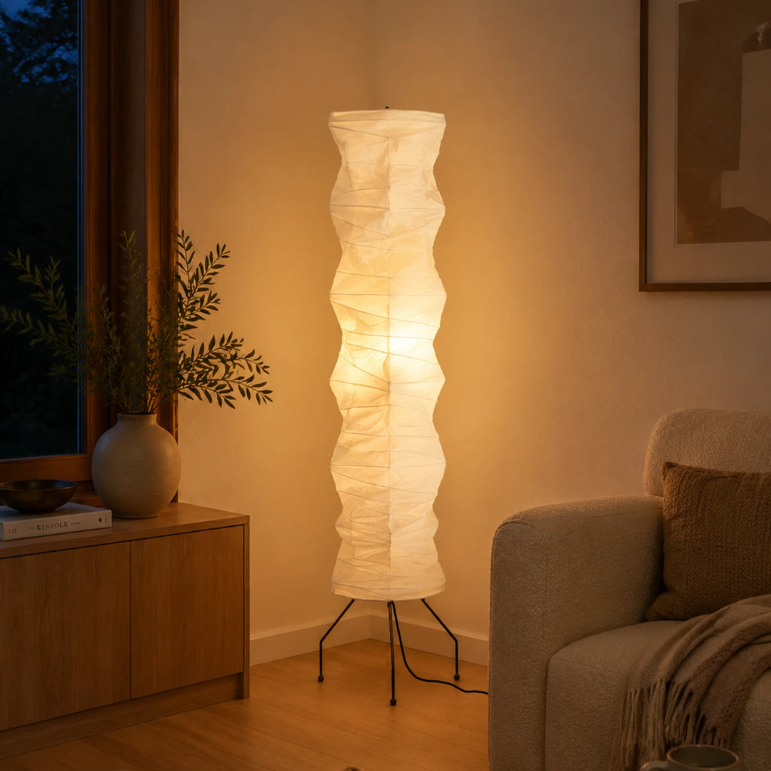 Handcrafted paper floor lamp glowing beside a wooden sideboard in a warm evening room