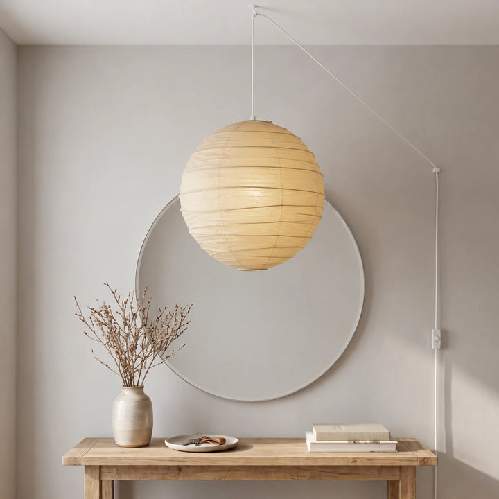 Handcrafted paper globe pendant above a console with a round mirror and vase