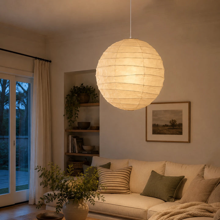 Paper globe lamp hanging in a room with tall garden-facing glass doors