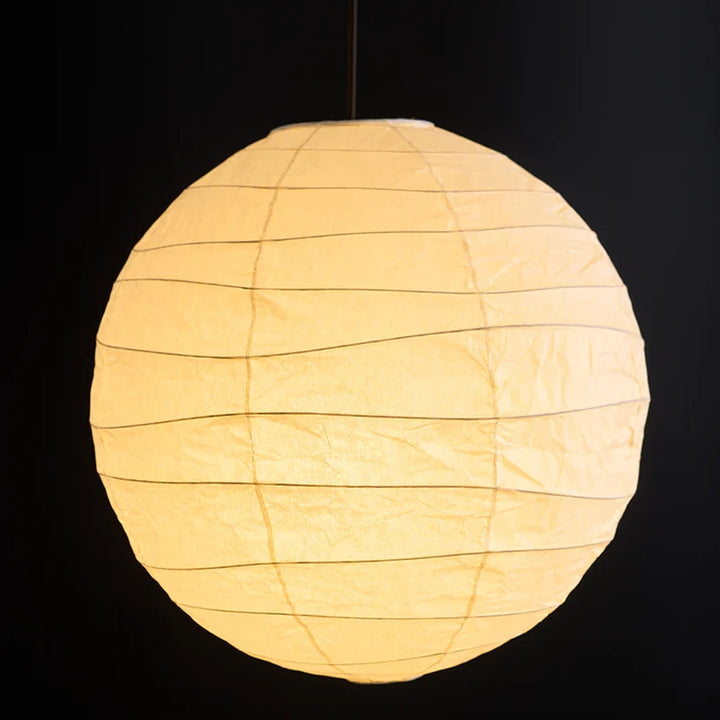 Paper globe lamp glowing warm amber against a black backdrop