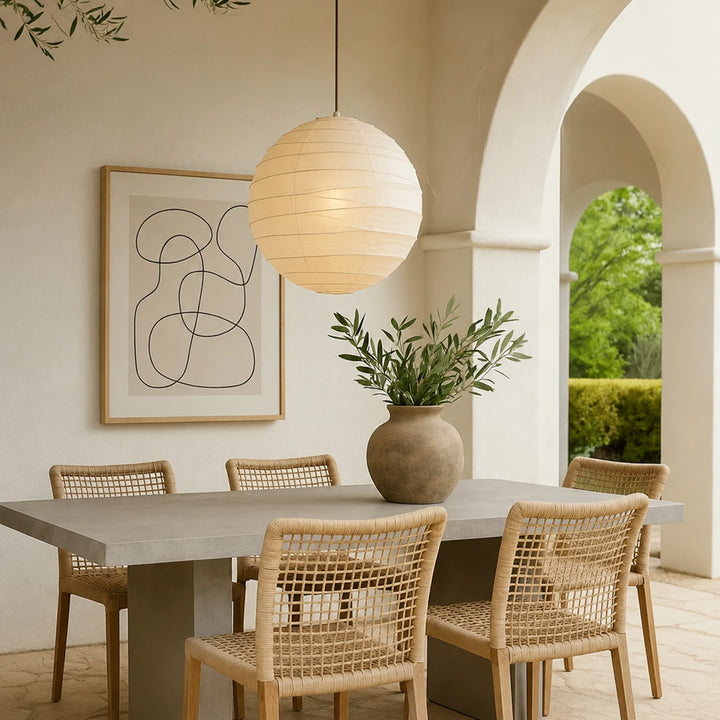 Japandi paper pendant hanging above a wooden dining table with arched doorway