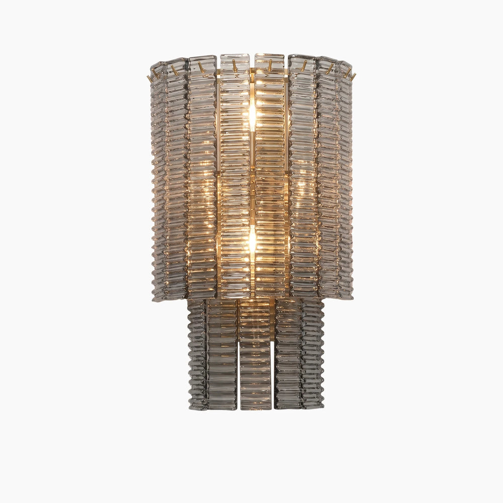 Layered glass rod wall light glowing warm against a soft neutral backdrop