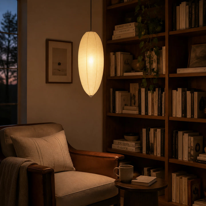 Oval paper pendant in a book-lined nook beside a reading armchair