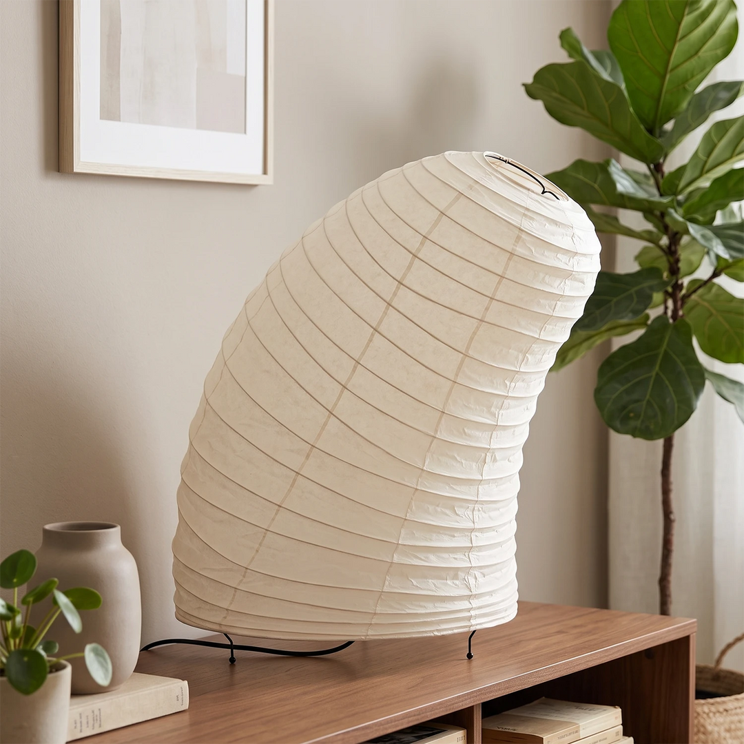 Sculptural paper lamp on a bench in a living room beside a large indoor tree