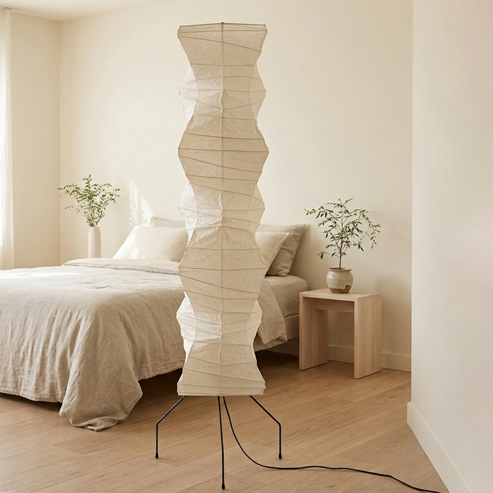 Minimalist paper floor lamp beside a bed in a bright white bedroom