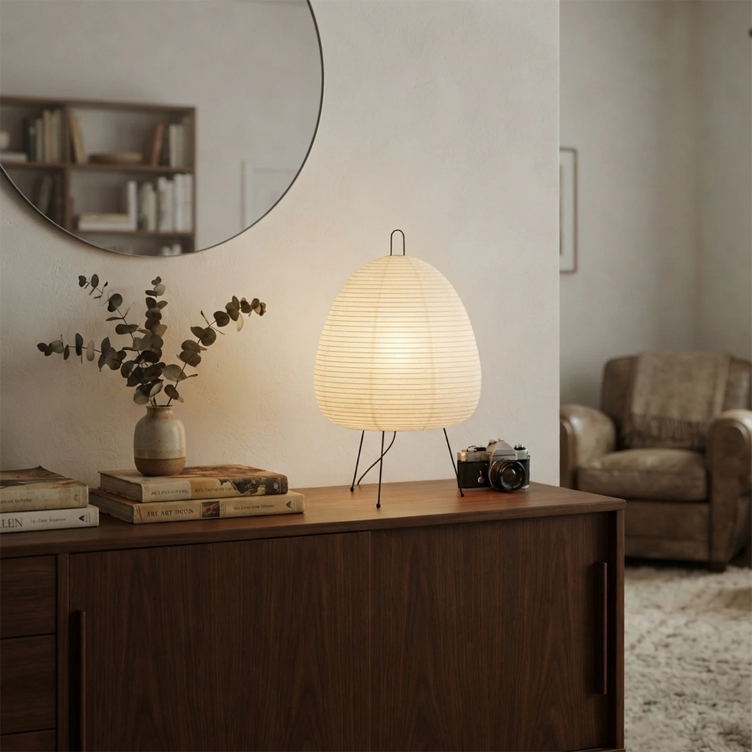 Paper table lamp on a hallway sideboard beside a round mirror and dried stems