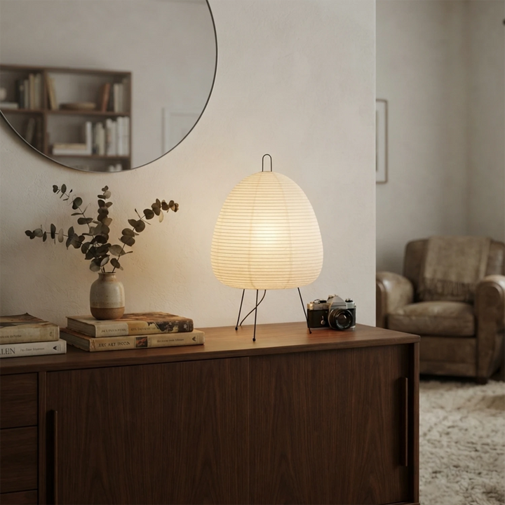 Paper table lamp on a hallway sideboard beside a round mirror and dried stems