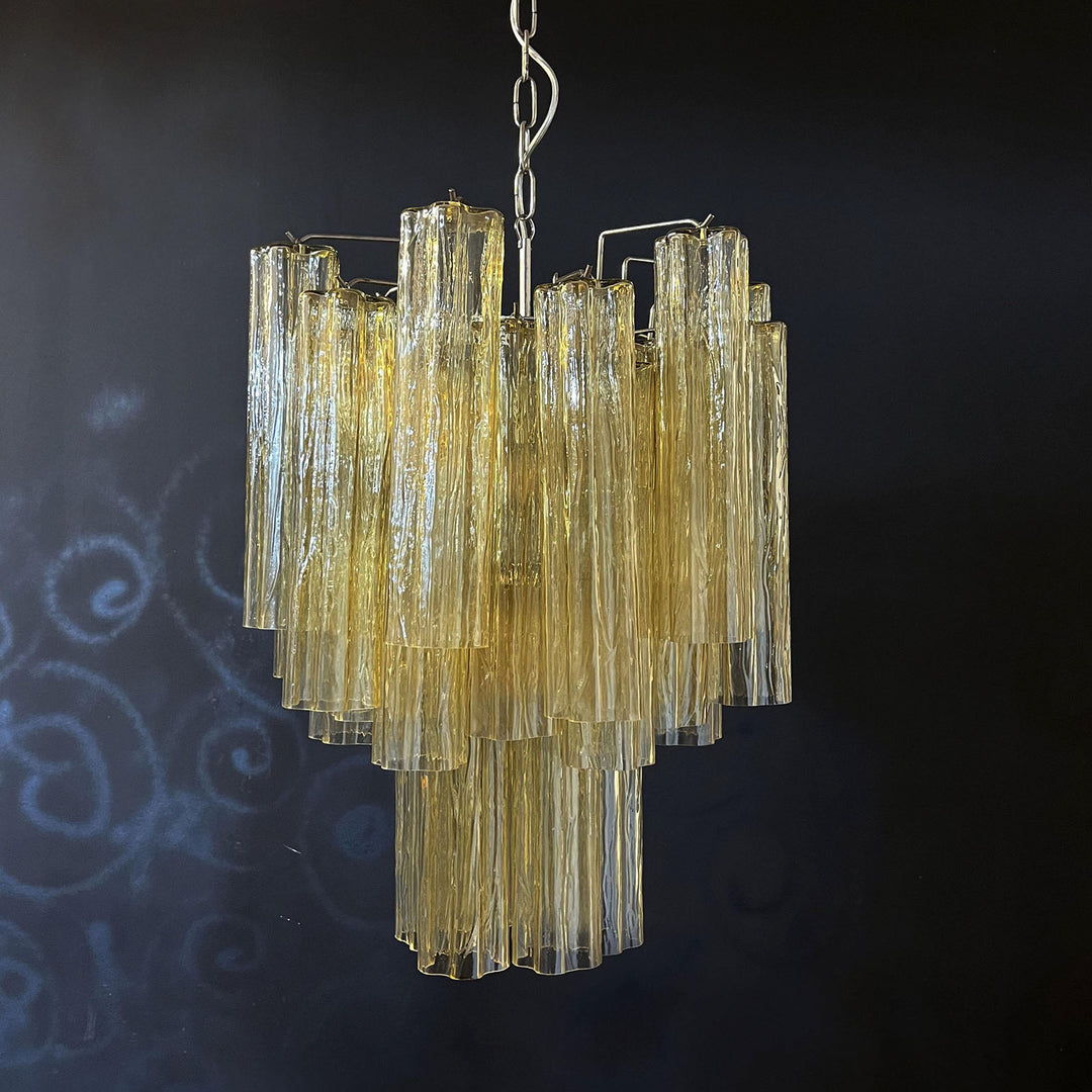 Murano Glass Tube Chandelier with amber gold glass against a black wall with a smoky background