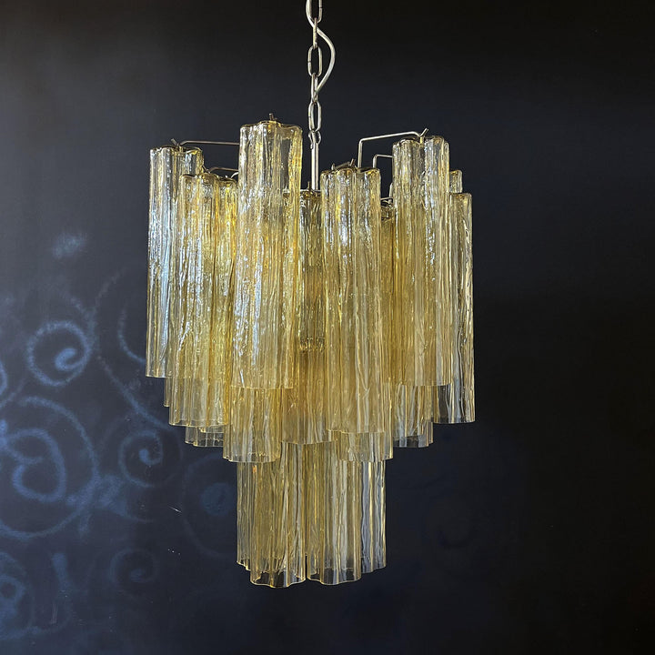Murano Glass Tube Chandelier with amber gold glass against a black wall with a smoky background