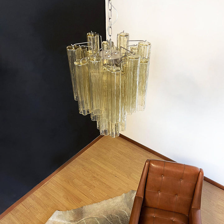 Murano Glass Tube Chandelier with amber gold glass against a black wall with a leather chair
