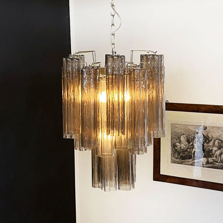 Murano Glass Tube Chandelier with amber gold glass lit with warm light in a corner view
