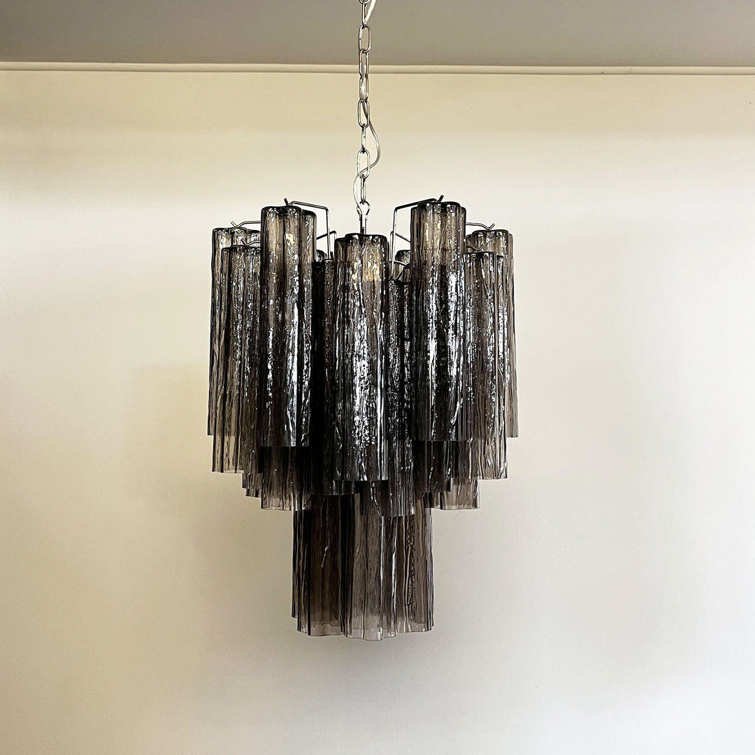 Murano Glass Tube Chandelier with smoke gray glass against a black wall with smoky background