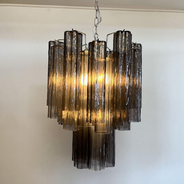 chandelier-smoke-gray-lit-corner-woorglamp	Murano Glass Tube Chandelier with smoke gray glass lit with warm light in a corner view