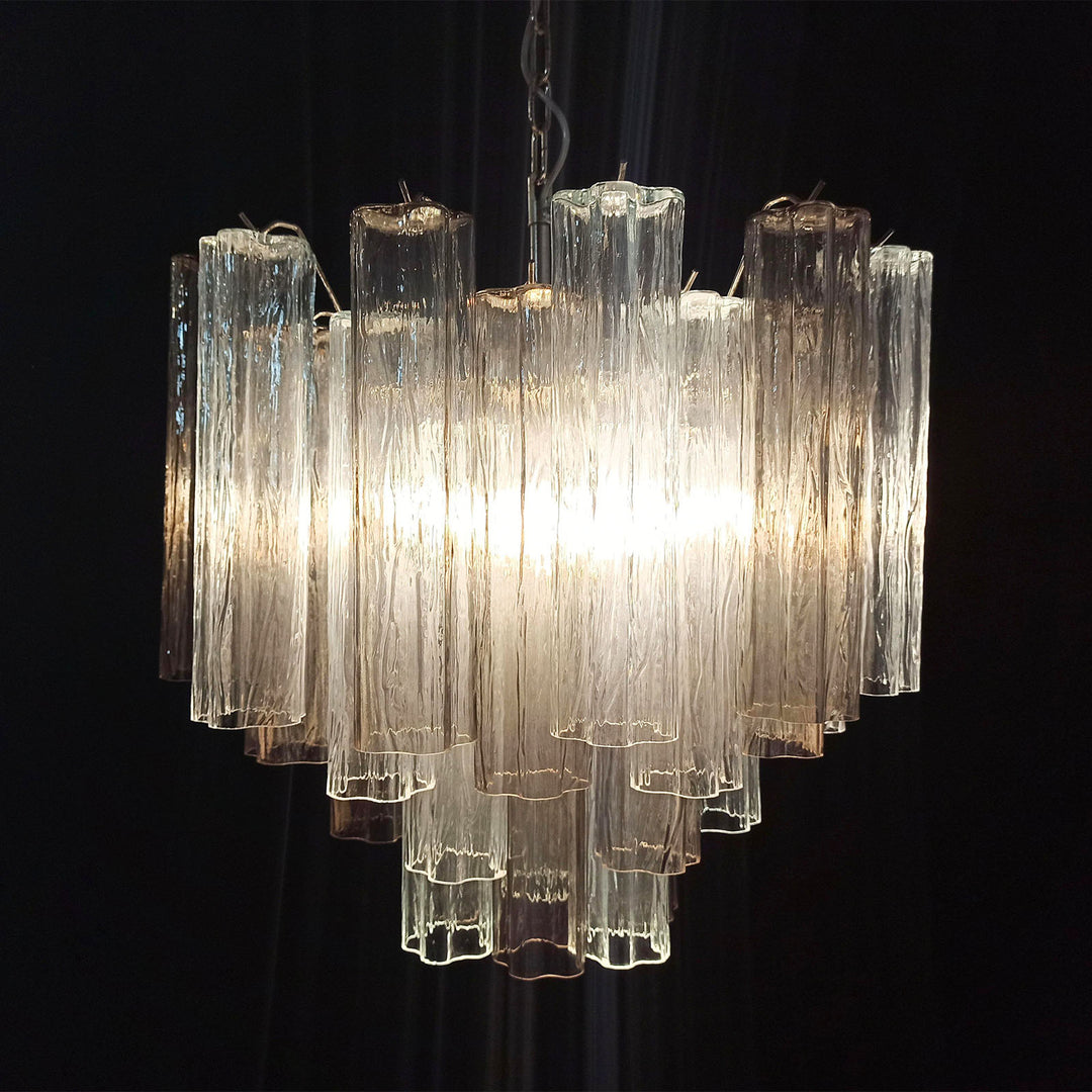 Lit Murano Star Tube Chandelier with clear glass tubes against a dark accent wall