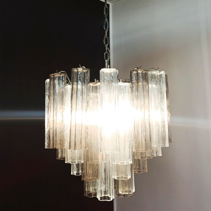 Lit Murano Star Tube Chandelier with clear glass tubes against a dark accent wall