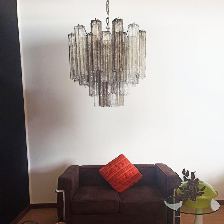 Murano Star Tube Chandelier with vibrant purple glass against a black accent wall with a gold sofa
