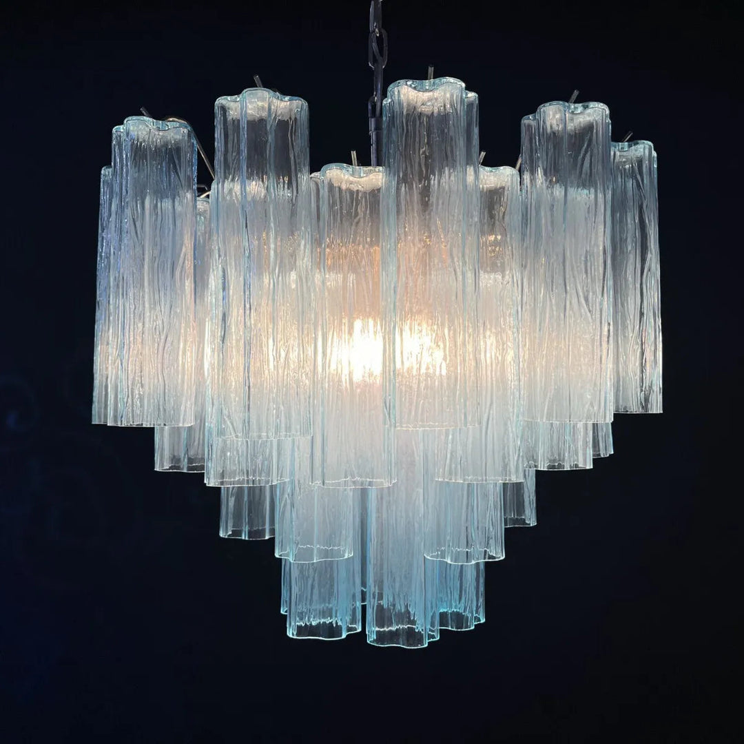 Lit Murano Star Tube Chandelier with turquoise blue glass tubes against a dark accent wall