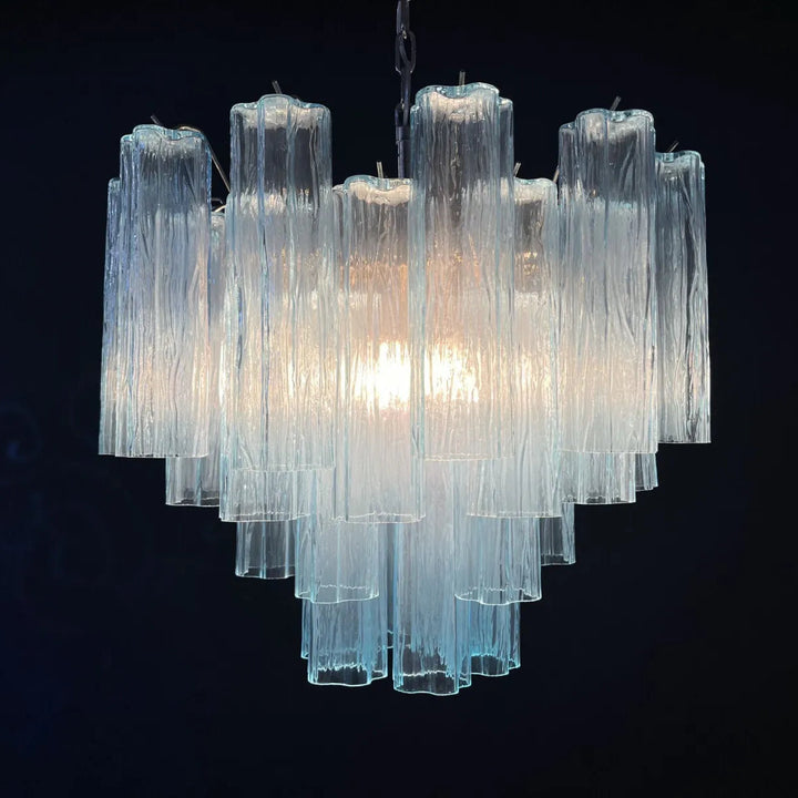 Lit Murano Star Tube Chandelier with turquoise blue glass tubes against a dark accent wall