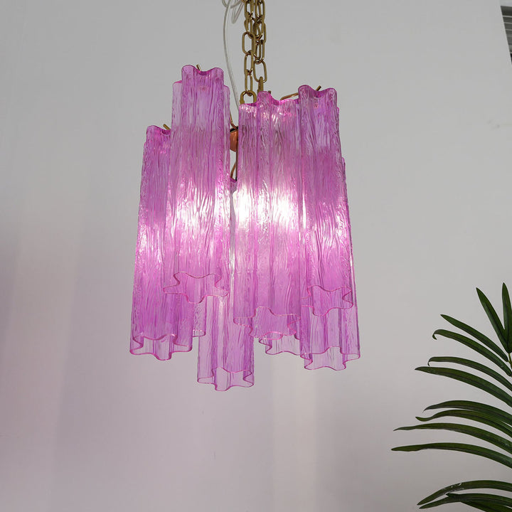 Murano Tubes Glass Chandelier with vibrant purple glass on a plain white wall with tropical plants