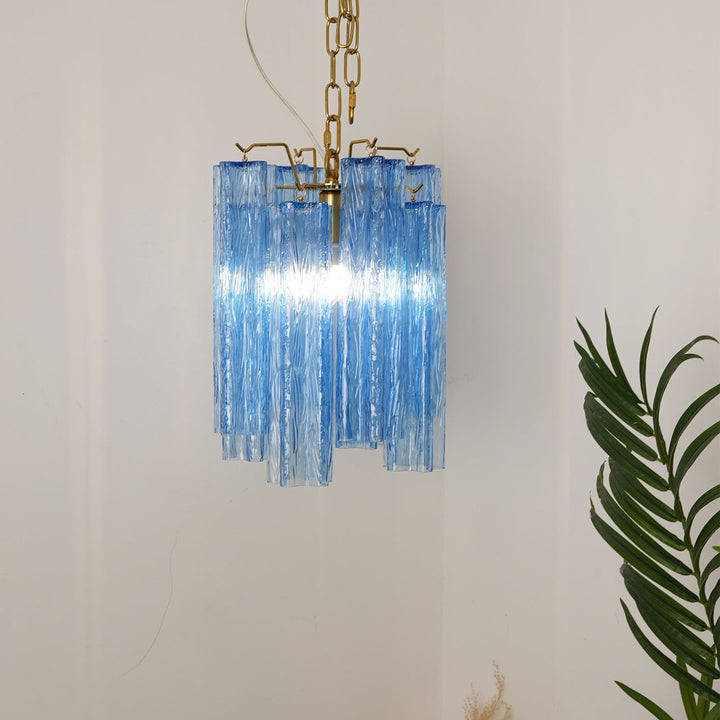 Murano Tubes Glass Chandelier with bright blue glass on a plain white wall with tropical plants