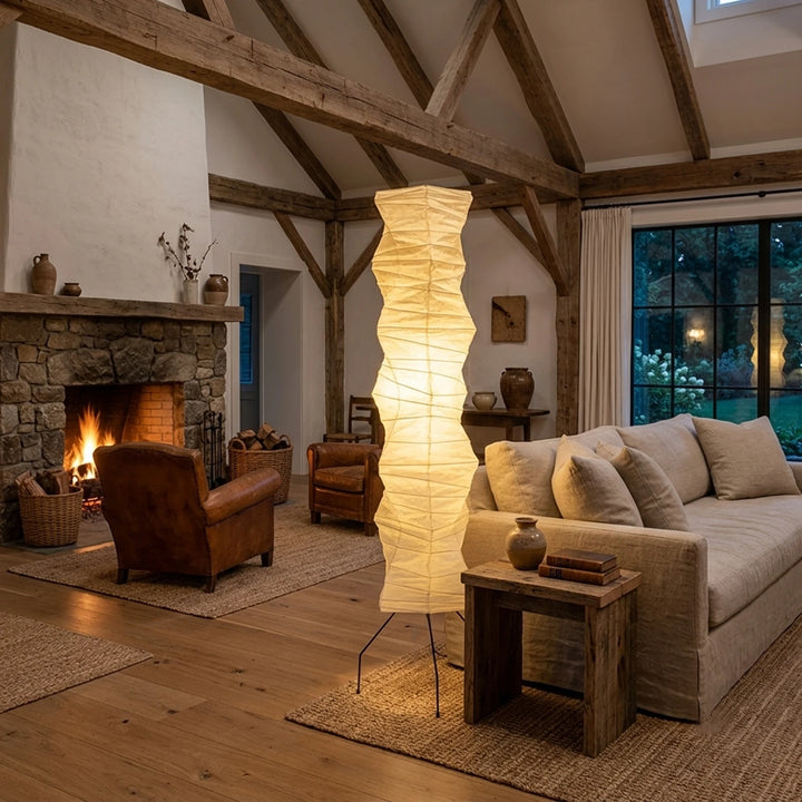 Oversized paper floor lamp in a timber-beamed living room with a lit fireplace