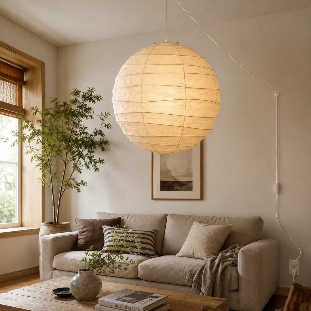 Oversized paper pendant above a sofa in a living room framed by indoor plants