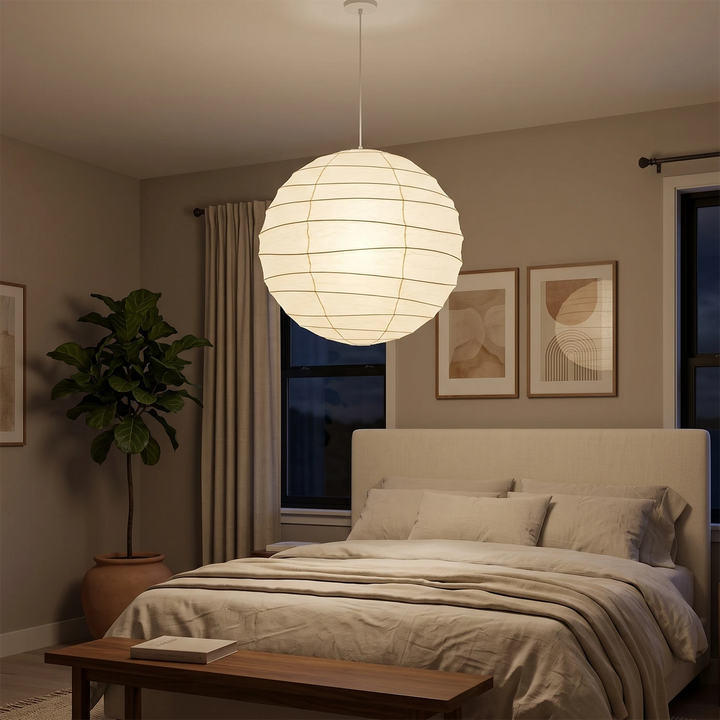 Paper pendant glowing warm in a panelled bedroom at evening