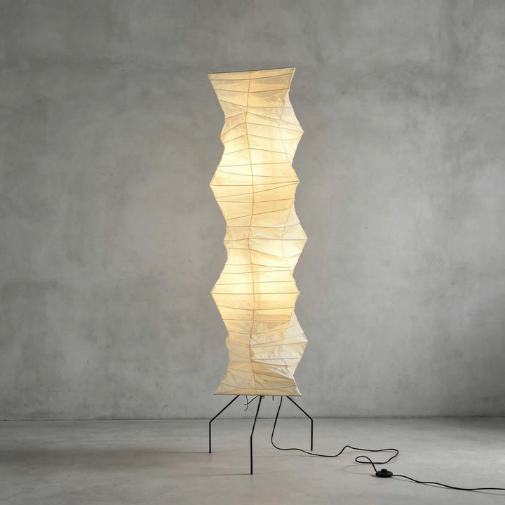 Paper floor lamp lit against a textured concrete studio backdrop