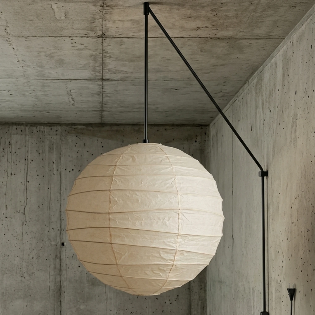 Paper globe pendant on a black swag cord mounted against a concrete wall