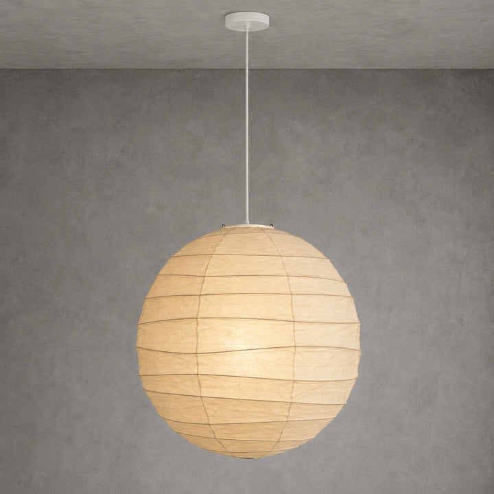 Paper globe pendant on a white cord hanging against a textured grey wall